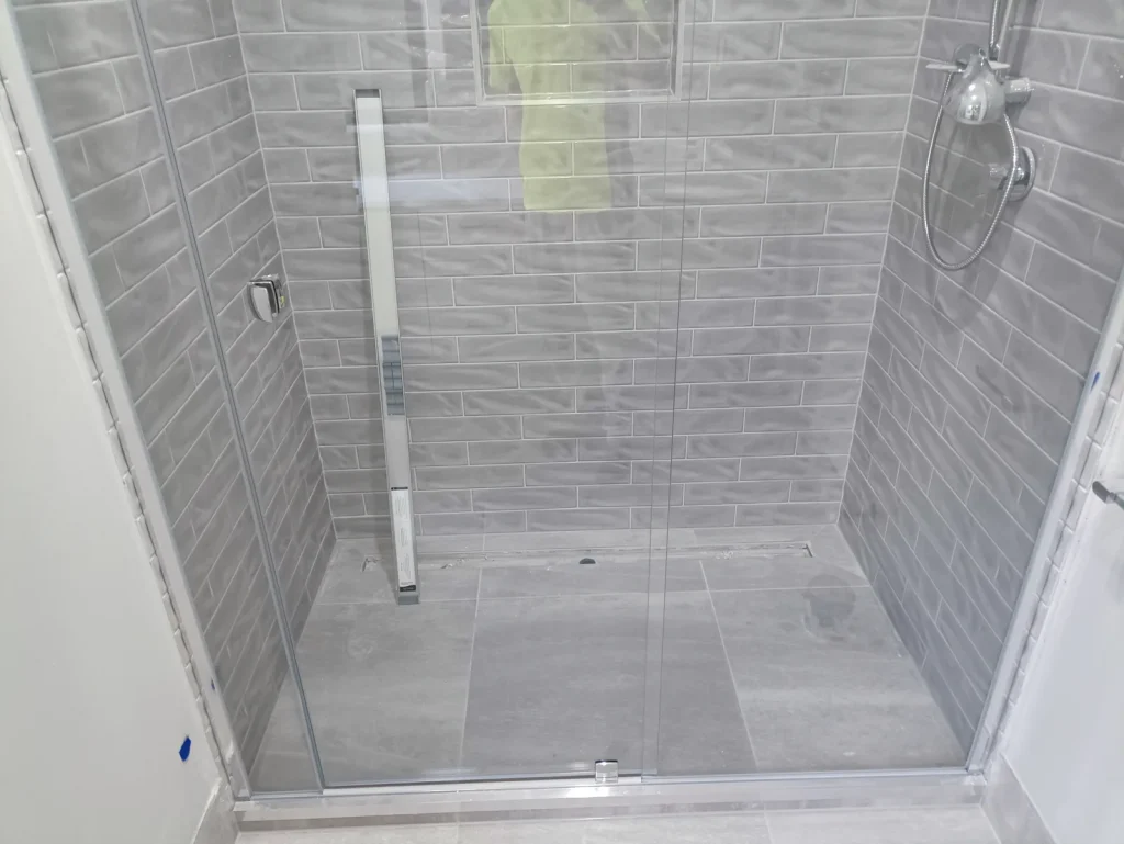 Frameless glass shower screen sealed to grey subway tiles, Melbourne