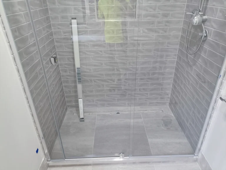 Frameless glass shower screen sealed to grey subway tiles, Melbourne